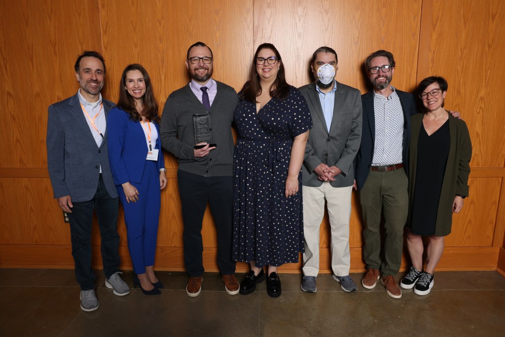 A picture of K. Chad Clay standing with a group of his spouse and friends and holding an award